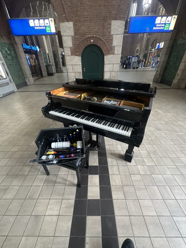 Vleugel in een stationshal, met geopende gereedschapskoffer ernaast