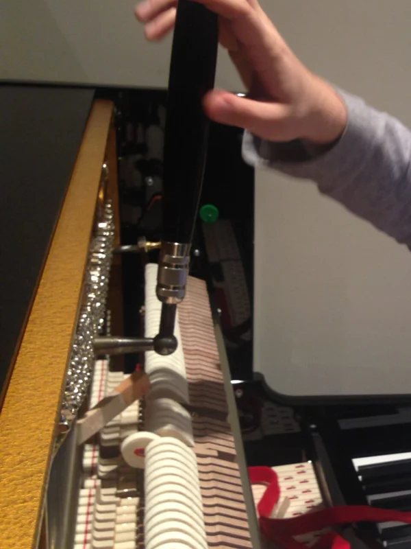 Hand met stemhamer op de stempennen van een piano